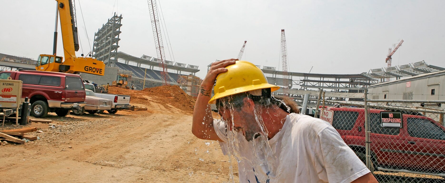 Foto: Ein Bauarbeiter schüttet sich Wasser aus seinem Schutzhelm über den Kopf, während er bei großer Hitze in der Nähe eines Baseballstadions in Washington, DC, arbeitet. (Foto: Mark Wilson/Getty Images).